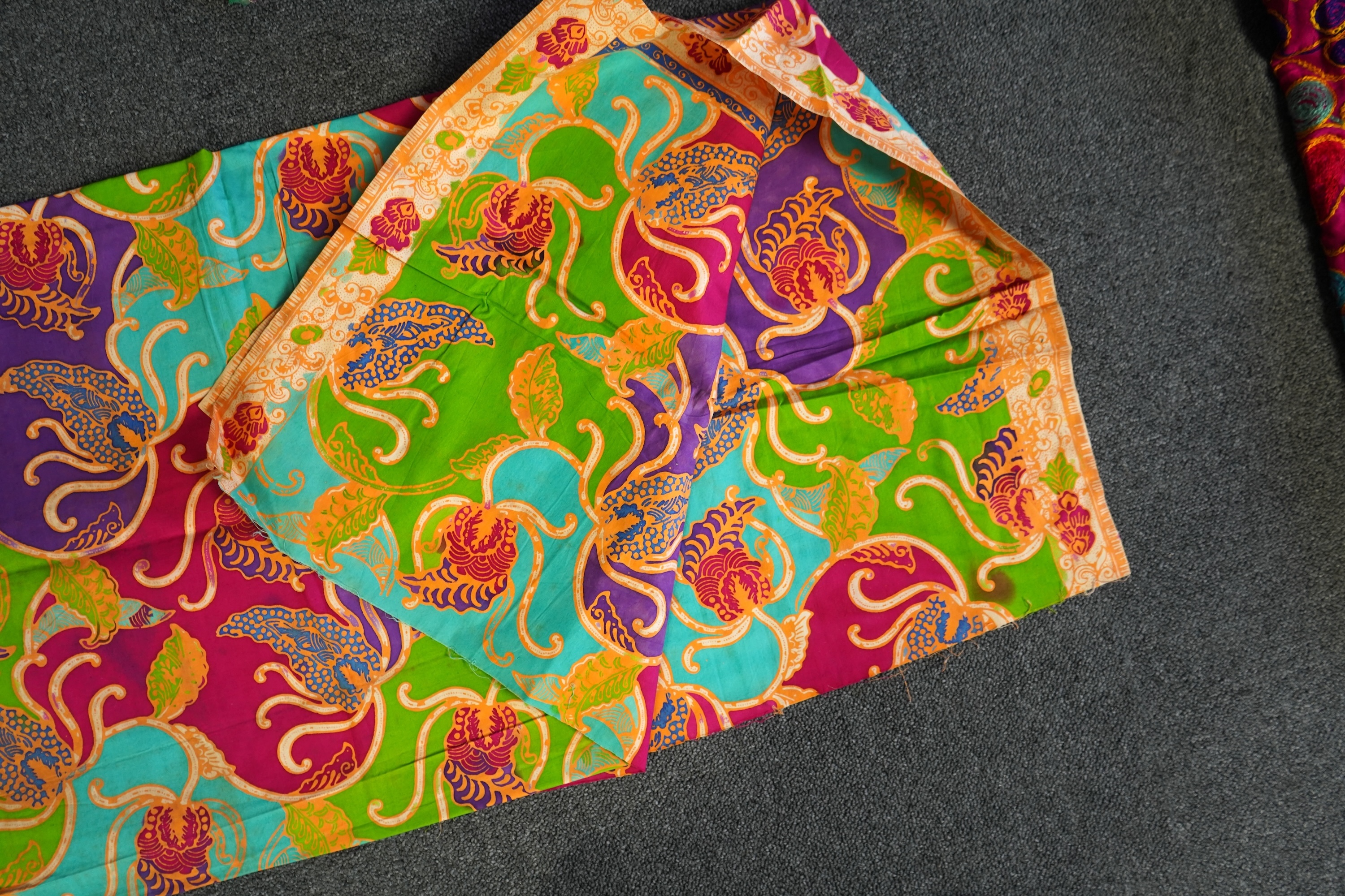 A large Indian silk embroidered and mirrored temple pelmet, with a cerise silk embroidered hanging and a length of cotton wax resist style printed fabric. Temple pelmet 468cm long x 70cm, deep. Condition - the pelmet has